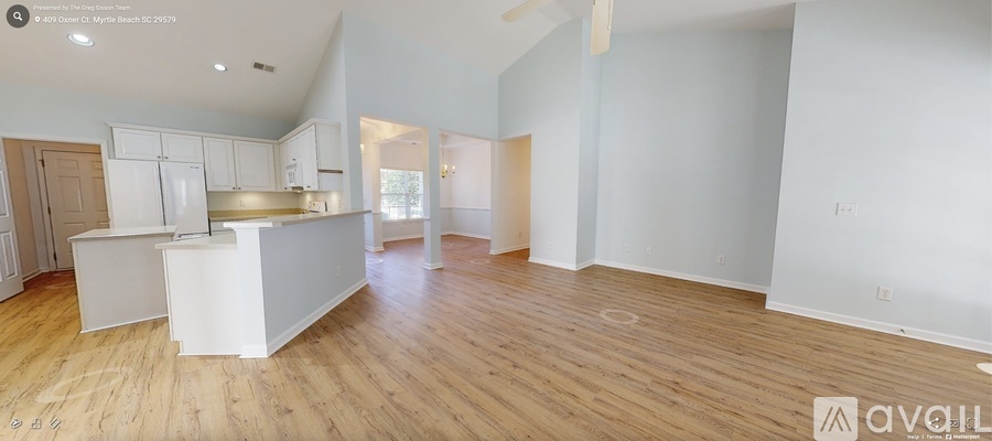 A spacious kitchen with white cabinets and a wooden floor.
