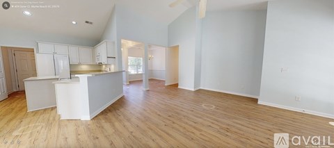 A spacious kitchen with white cabinets and a wooden floor.
