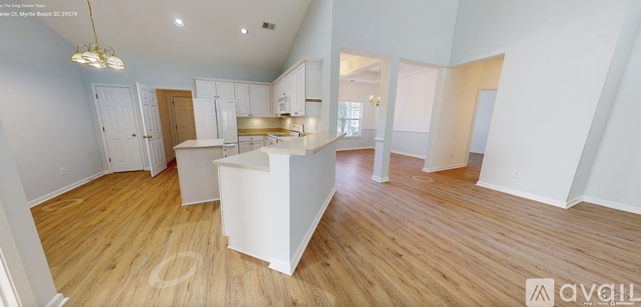 A large, empty living space with wooden floors and white walls.