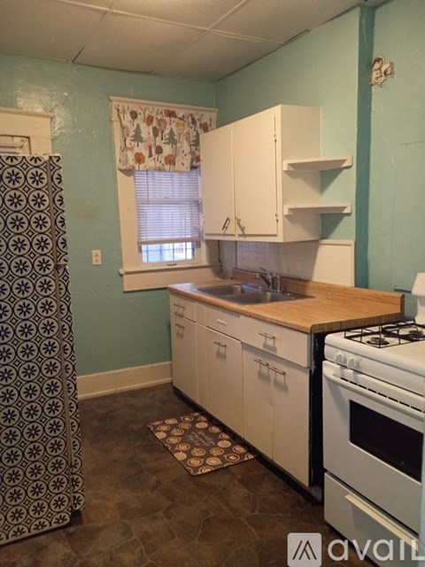 A kitchen with a white stove and cabinets.