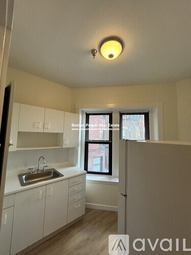 A kitchen with white cabinets and a window.