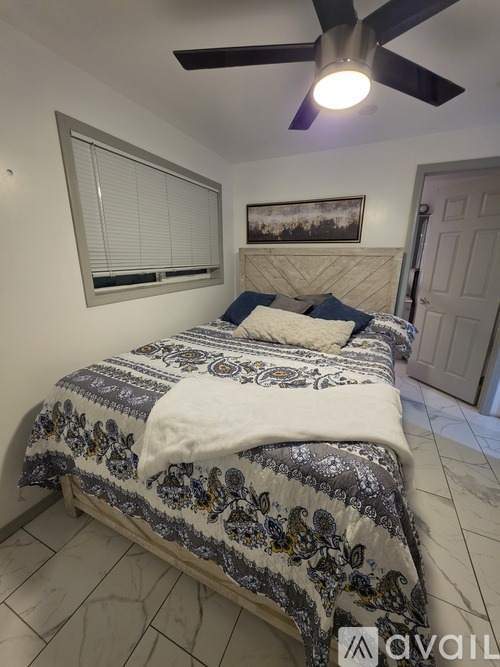A bedroom with a bed covered in a blue and white patterned comforter.