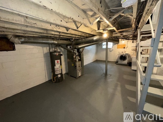 A spacious basement with a concrete floor, white walls, and a metal staircase.