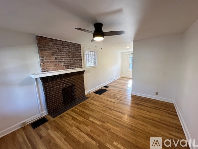 A room with a brick fireplace and wooden flooring.