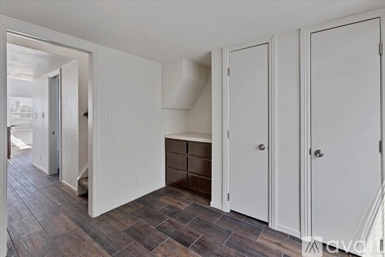 A room with a white door and a brown floor.