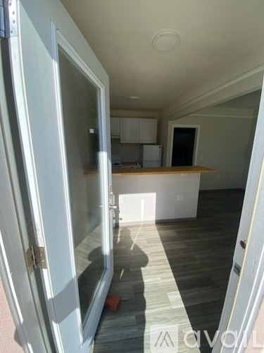 A white door is open to a room with a wooden floor.