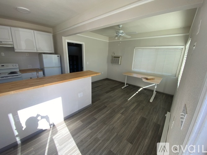 A kitchen with a refrigerator, stove, and a dining table with chairs.