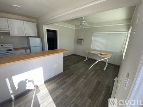 A kitchen with a refrigerator, stove, and a dining table with chairs.