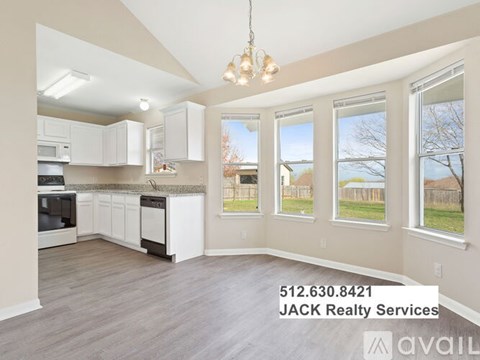 A kitchen with white cabinets and a window overlooking a fence.