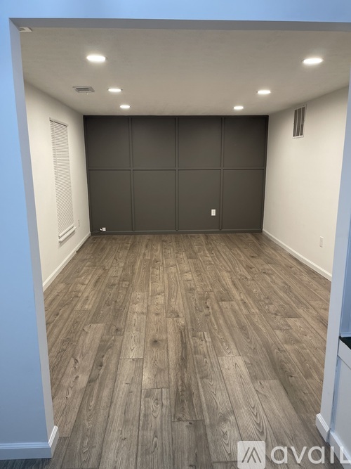 A room with wooden flooring and a grey partition wall.