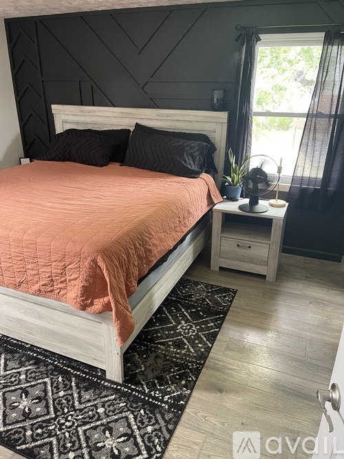 A bedroom with a white bed and a black and white rug.