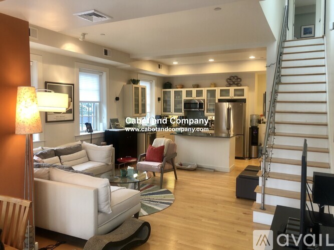 A living room with a staircase and a glass table.
