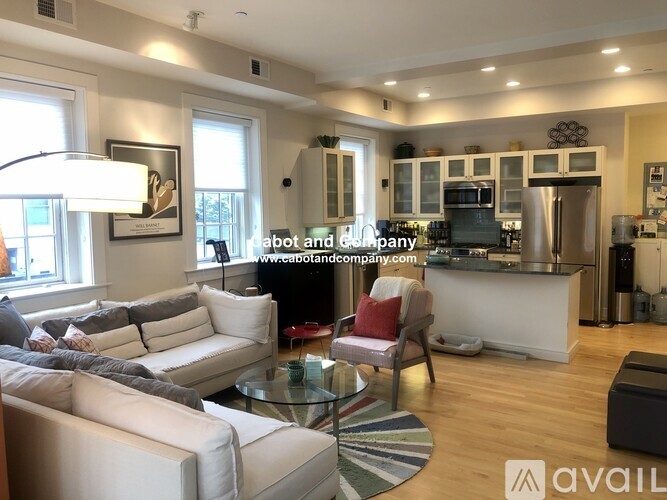 A modern living room with a kitchen in the background.