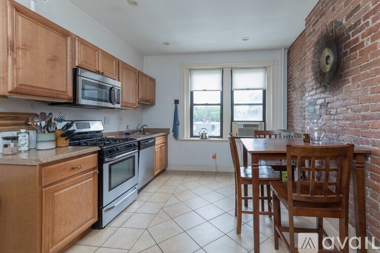 A kitchen with wooden cabinets and a brick wall.