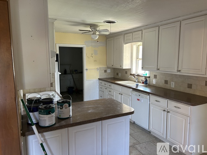 A kitchen with white cabinets and brown countertops is under renovation.