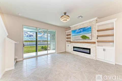 A spacious living room with a fireplace and a painting of a beach scene on the wall.