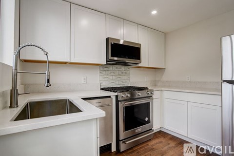 A modern kitchen with white cabinets and stainless steel appliances.