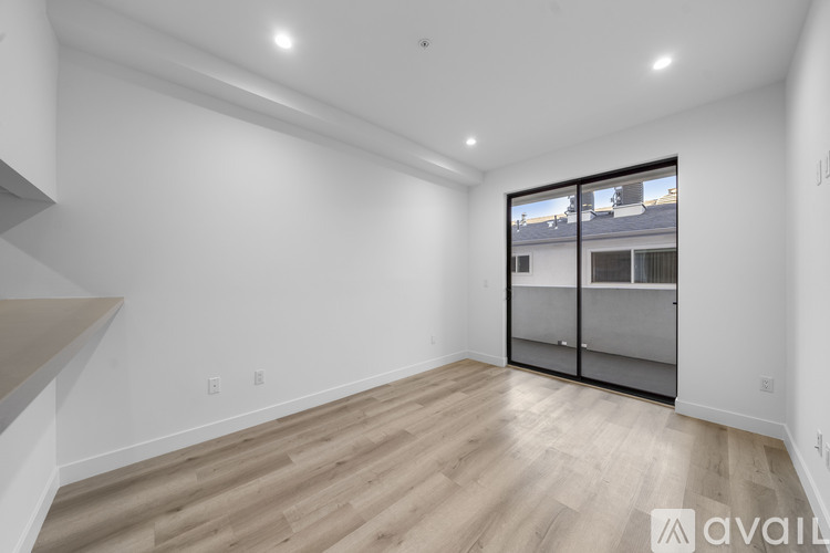 A spacious room with wooden flooring and a large window with a view of a building.