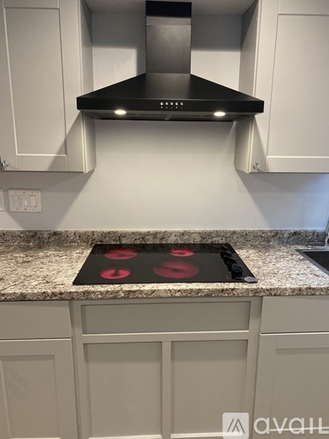 A kitchen with a black stove top and white cabinets.