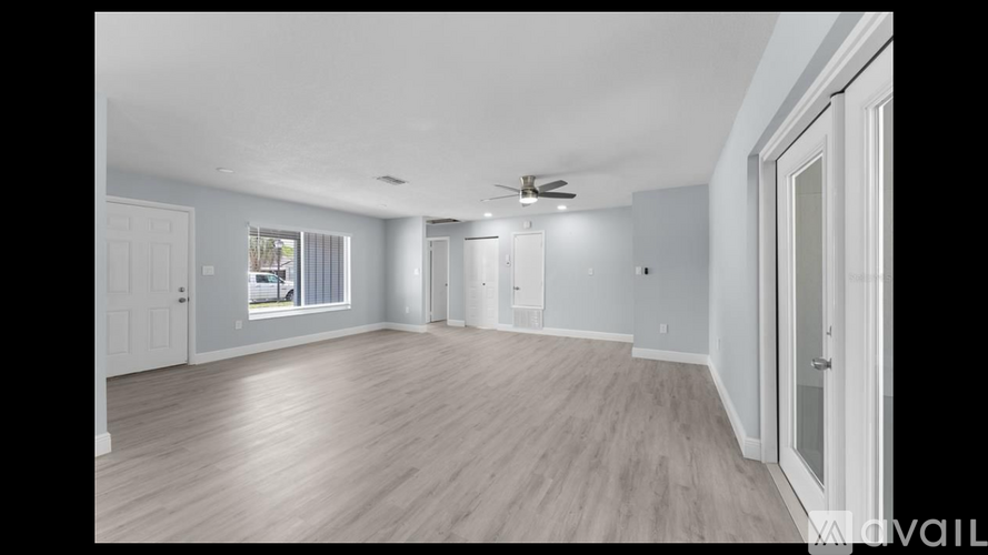 A spacious room with wooden flooring and white walls.