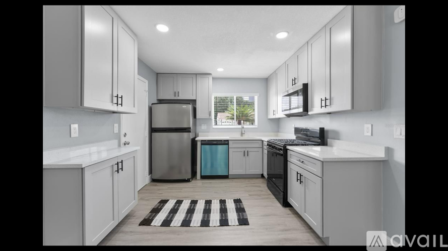 A modern kitchen with white cabinets and a black and white rug on the floor.