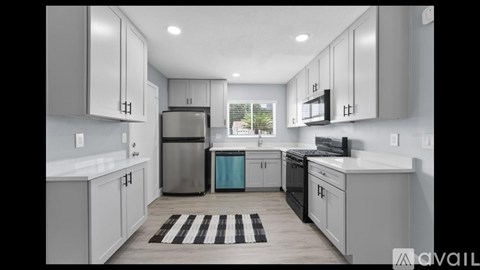 A modern kitchen with white cabinets and a black and white rug on the floor.