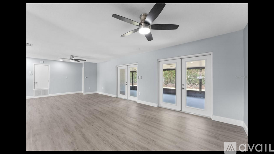 A room with a ceiling fan and sliding glass doors.