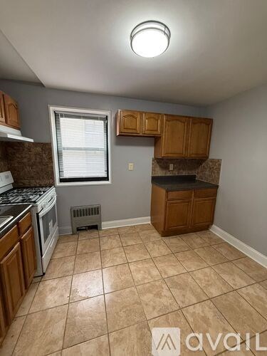 A kitchen with tile flooring and wooden cabinets.