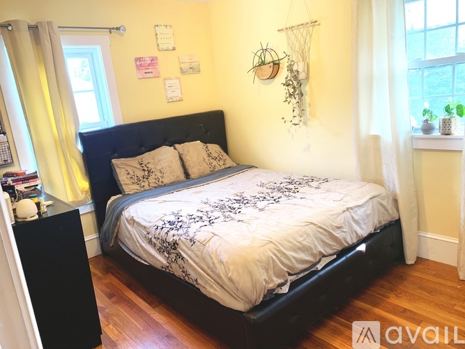 A bedroom with a bed, a nightstand, and a window.