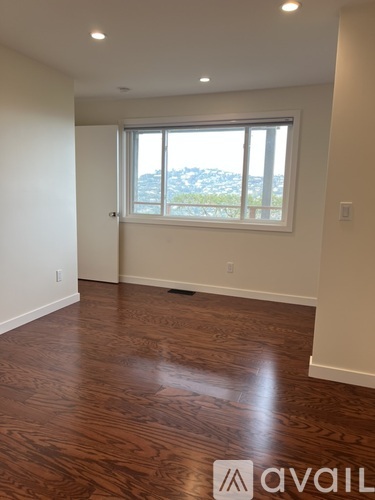 A room with wooden flooring and a large window overlooking a landscape.