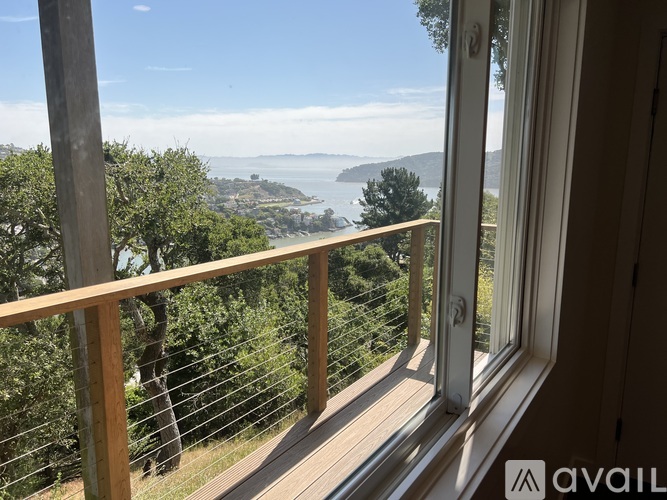 A balcony with a view of the sea and trees.