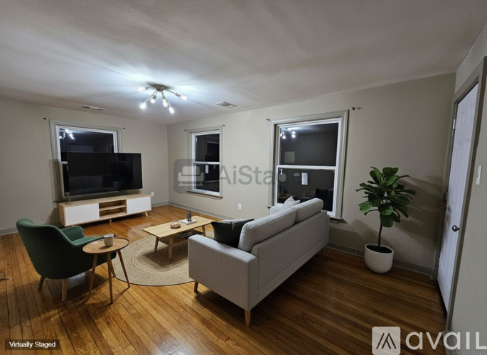 A living room with a green chair, a white couch, and a wooden floor.