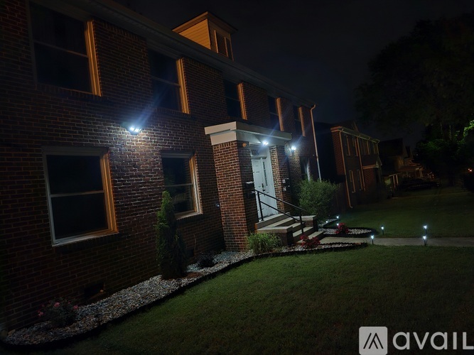 A building with lit windows and a garden in front at night.