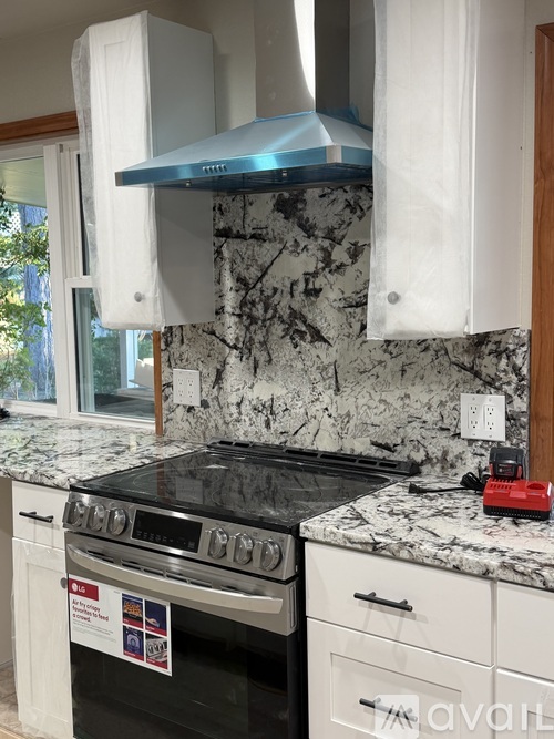 A kitchen with a black stove top oven and a marble counter top.