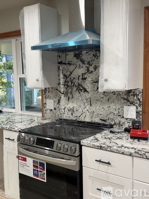 A kitchen with a black stove top oven and a marble counter top.