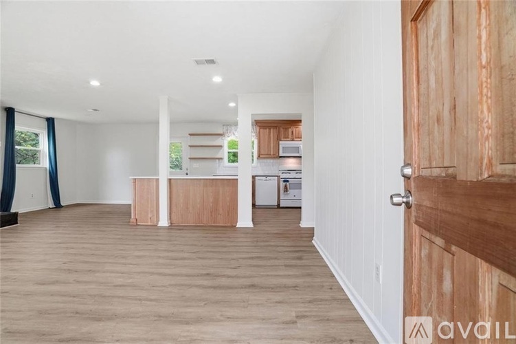 A spacious room with wooden floors and a kitchen area in the background.