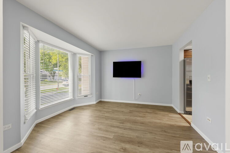 A spacious room with a television and a window with blinds.