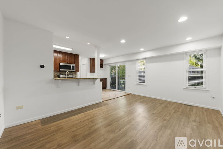 A spacious room with wooden flooring and a kitchen area with a microwave and oven.