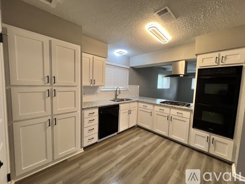 A kitchen with white cabinets and wooden floors.