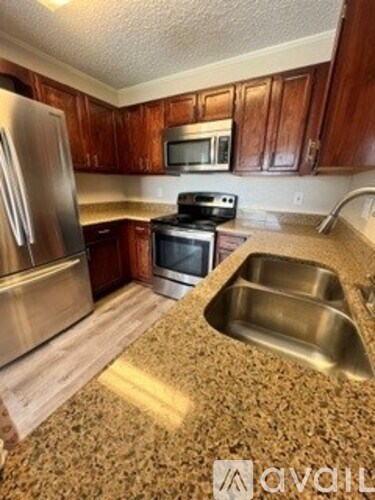 A kitchen with a stainless steel refrigerator, microwave, oven, and sink.