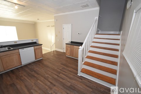 A kitchen with wooden floors and a staircase with wooden steps.
