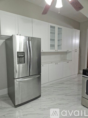 A stainless steel refrigerator in a kitchen with white cabinets.