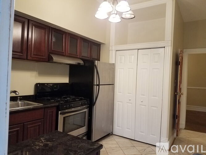 A kitchen with dark wood cabinets and a black refrigerator.