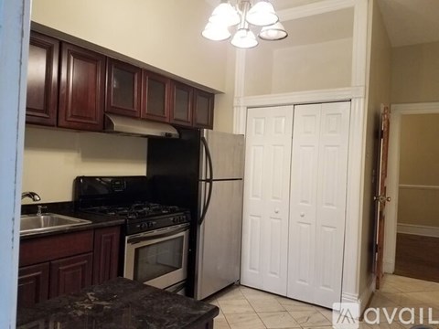 A kitchen with dark wood cabinets and a black refrigerator.