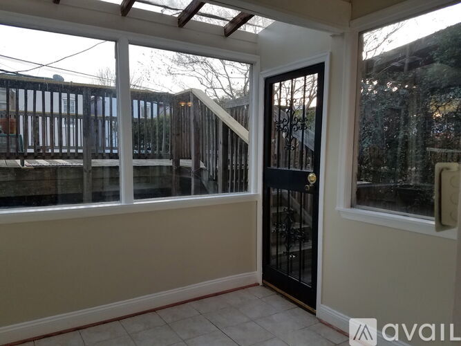 A room with a black door and a balcony with a railing.