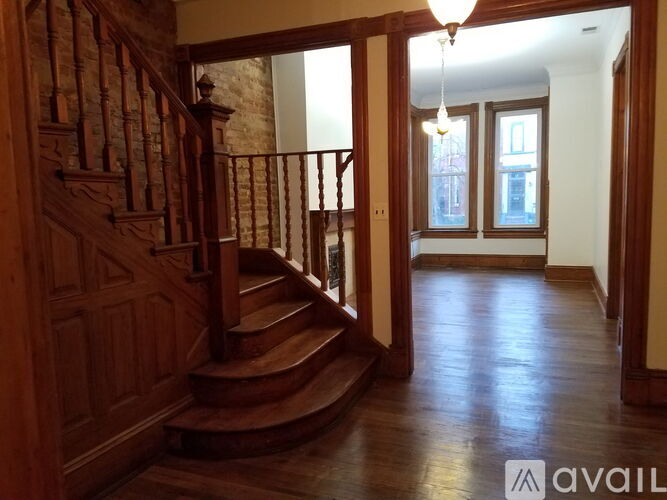 A wooden staircase with a metal railing leads to a bright room with a window.