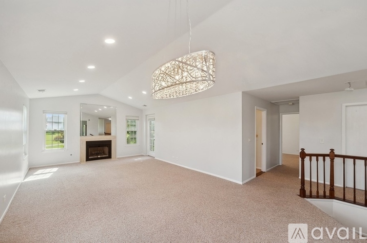 A spacious living room with a fireplace and a chandelier.