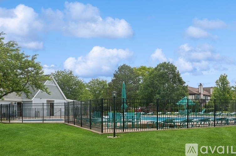 A pool surrounded by a black fence with a small white building in the background.