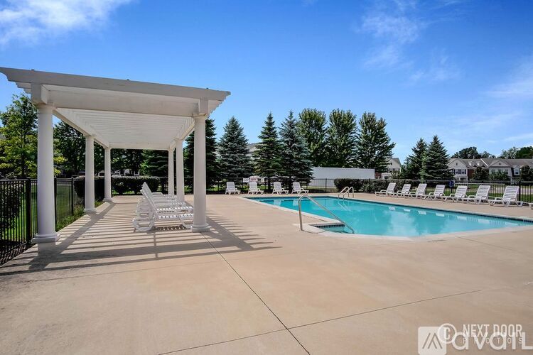A pool area with a white pergola and lounge chairs.