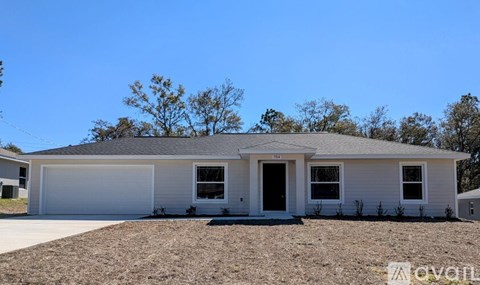 A white house with a grey roof and a garage door.